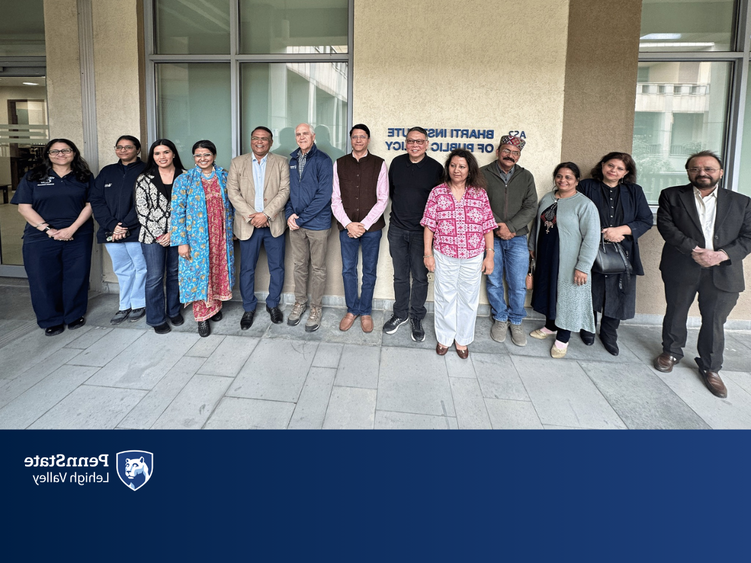 faculty members stand in front of an academic building 